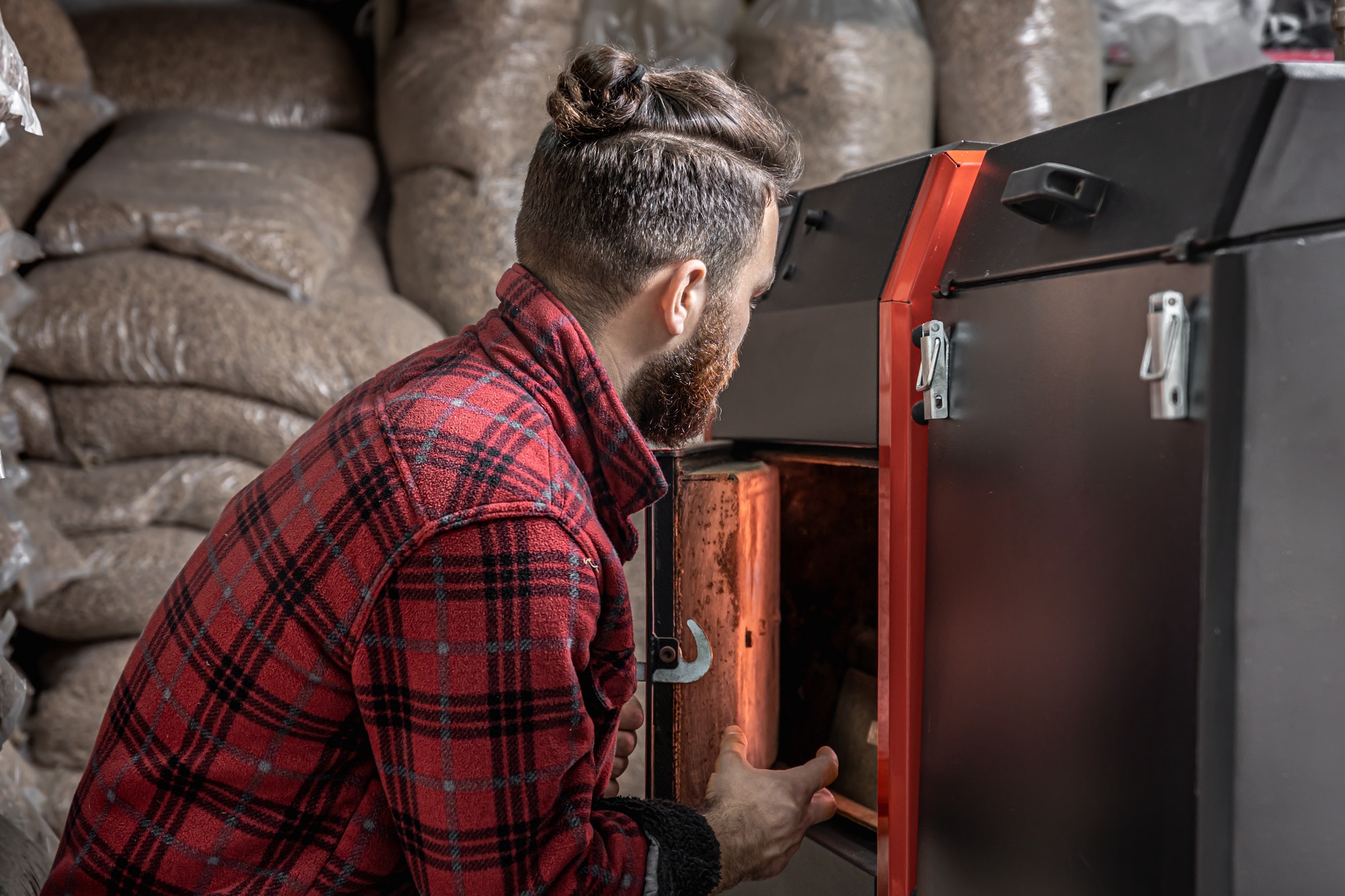 The young man with solid fuel boiler, working with biofuels, economical heating.